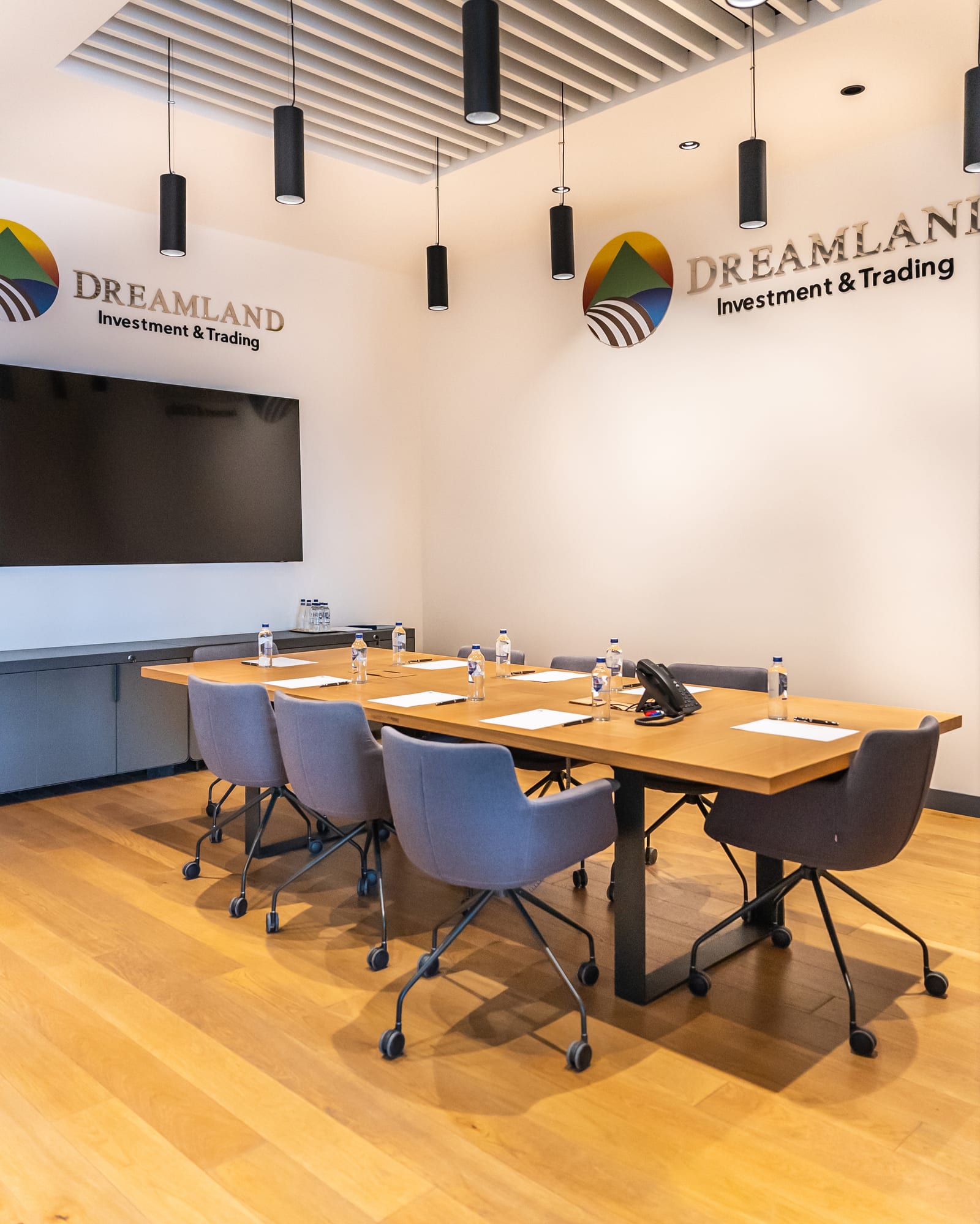 Dreamland boardroom: a long oak table beneath pendant lights, the Dreamland mark on the wall